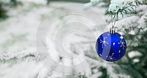 New year decoration blue ball on a snow-covered branch. Christmas tree toy on the branches of a Christmas tree covered with snow