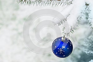 New year decoration blue ball on a snow-covered branch. Christmas tree toy on the branches of a Christmas tree covered with snow