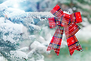 New year decoration red big bow on a snow-covered branch. Christmas tree toy on the branches of a fir tree covered with snow,