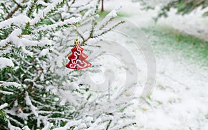 New year decoration red shiny Christmas tree-toy on a snow-covered branch. Shiny Christmas tree toy on the branches of