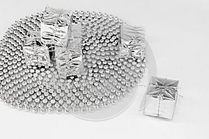 New year decoration - silver small gifts, shiny toys on spiral beads, chain of balls on a white backdrop. Christmas