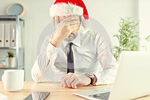 New Year depression, businessman in office wearing Santa Claus hat feeling lonely and depressed