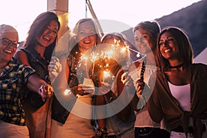 New year eve celebration with group of mixed ages and generations women having fun with sparklers outdoor - people having fun