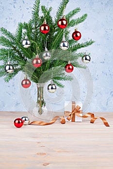 New Year festive greeting card design, Christmas decorations silver and red balls on green fir branches in glass vase, gift box