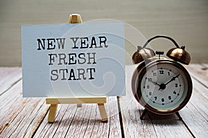 New year fresh start word with alarm clock on wooden background