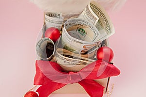 New year gift box with dollars on pink background close up