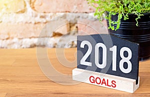 New year 2018 goals on blackboard sign and green plant on wood t