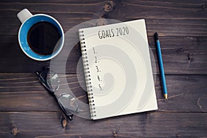 New Year goals, resolution or action plan 2020 concep. Office wood table with blank notepad, pencil, glasses, phone and cup of