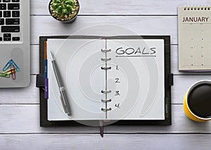 New Year goals, resolution or action plan concept. Notebook on table with laptop, calendar, coffee and plant. Flat lay top view