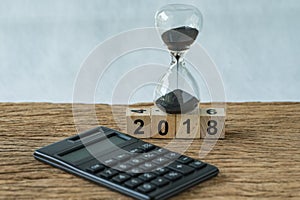 new year 2018 goals, target minimal concept as number 2018 wooden cube block with sandglass and calculator on wooden table