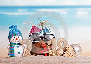 New Year inscription 2018, coconut with straws, snowman, Christmas tree, Christmas ball and starfish on sand.