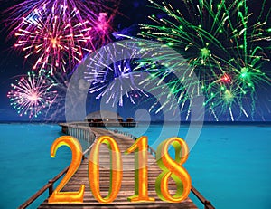 New Year inscription 2018 on the wooden road over the sea and New Year`s fireworks