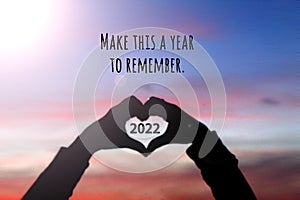 New year inspirational motivational quote - Make this a year to remember. Silhouette of a person holding a heart shaped hands.