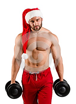 New year man with muscular body in red and white christmas santa hat standing on studio with white background