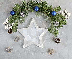 New year mockup: decorated christmas tree branches with white star shaped photo frame on grey background. Holidays concept