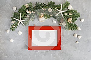 New year mockup: decorated with seashells and starfich pine tree branches with red photo frame on grey background. Tropical christ