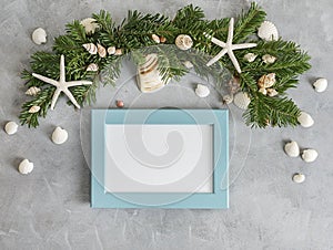 New year mockup: decorated with seashells and starfish pine tree branches with blue photo frame on grey background. Tropical chris