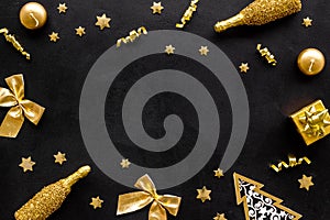 New Year mockup, gold color. Champagne, present box, decoration, balls on black background top-down frame copy space