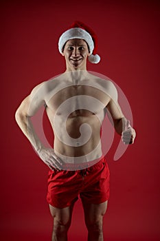 New year party for adult. macho man in santa hat. sexy santa claus red background. muscular bodybuilder guy. romantic photo