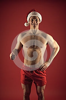 New year party for adult. macho man in santa hat. sexy santa claus red background. muscular bodybuilder guy. romantic photo