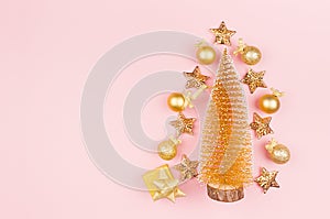 New Year party festive background - christmas tree with golden glossy, sparkling balls, ribbon, stars, gift on pink color backdrop