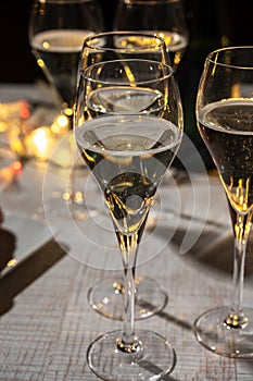 New year party, small bubbles of brut champagne cava or prosecco wine in tulip glasses with garland lights on background