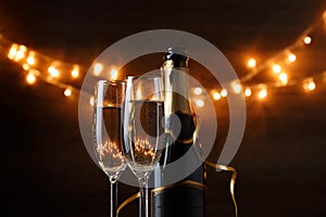 New Year photo of two wine glasses with wine, bottles, cork, burning garland