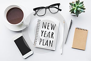 New year plan text on notepad with office accessories.