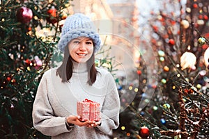 new year portrait of happy girl in oversize chunk knit hat on christmas shopping at city holiday market