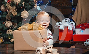 New year presents in gift box for kids. Smiling funny child in Santa hat holding Christmas gift in hand.