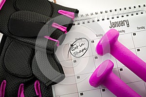 New year resolution and the desire to get in shape concept with a calendar with january first circled, gym equipment like purple