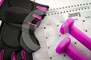 New year resolution and the desire to get in shape concept with a calendar with january first circled, gym equipment like purple