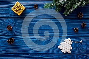 New year`s background. Christmas toys, present, spruce branches, pine cone on blue wooden background top view copyspace