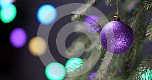New Year's ball of purple color on a fir branch moves across a beautiful background with shining lights, Christmas