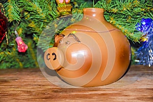 New Year`s card year of the pig piglet doll pots on the background of a dressed Christmas tree