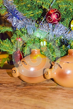 New Year`s card year of the pig piglet doll pots on the background of a dressed Christmas tree