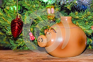 New Year`s card year of the pig piglet doll pots on the background of a dressed Christmas tree