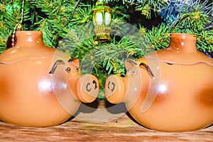 New Year`s card yearof the pig piglet doll pots on the background of a dressed Christmas tree