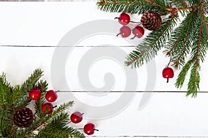 New Year`s, Christmas theme. Green fir branches with cones, decorative berries on white wooden background.