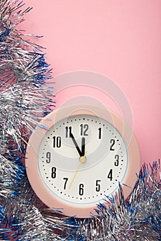 New Year`s clock decorated with christmas tinsel. Celebration Concept for New Year Eve. Vertical photo