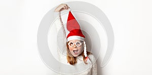 New Year`s commotion and confusion, a girl in a Santa Christmas hat holds a cap with his hand, isolated on a white background