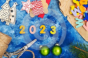 New Year`s composition. Numbers 2023. Christmas decorations, fir branches and cones on a blue background. View from above