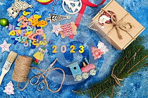 New Year`s composition. Numbers 2023. Christmas decorations, fir branches and cones on a blue background. View from above