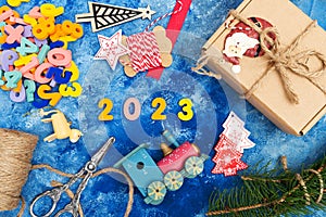 New Year`s composition. Numbers 2023. Christmas decorations, fir branches and cones on a blue background. View from above