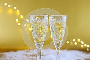 New Year`s composition: Two glasses with champagne on a gold bac