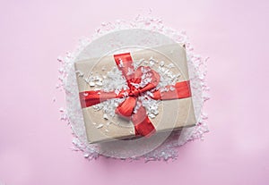 New Year`s concept, a box with gift, Christmas-tree toys are laid out on a pink background with snow flat lay