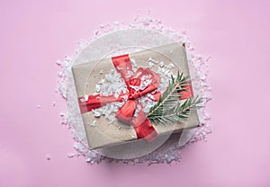 New Year`s concept, a box with a gift, Christmas-tree toys are laid out on a pink background with snow flat lay