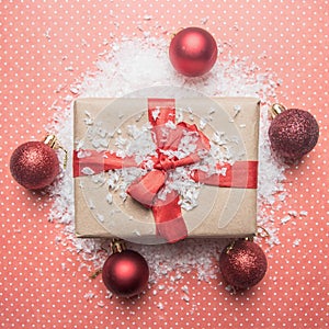 New Year`s concept, a box with a gift, Christmas-tree toys are laid out on a pink background with snow flat lay