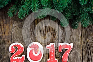 New Year's concept. Figure 2017 from gingerbread, fir branch on a wooden background, space for text