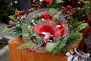 New Year`s decor in a basket of green coniferous branches, red leaves and berries under white snow on the table
